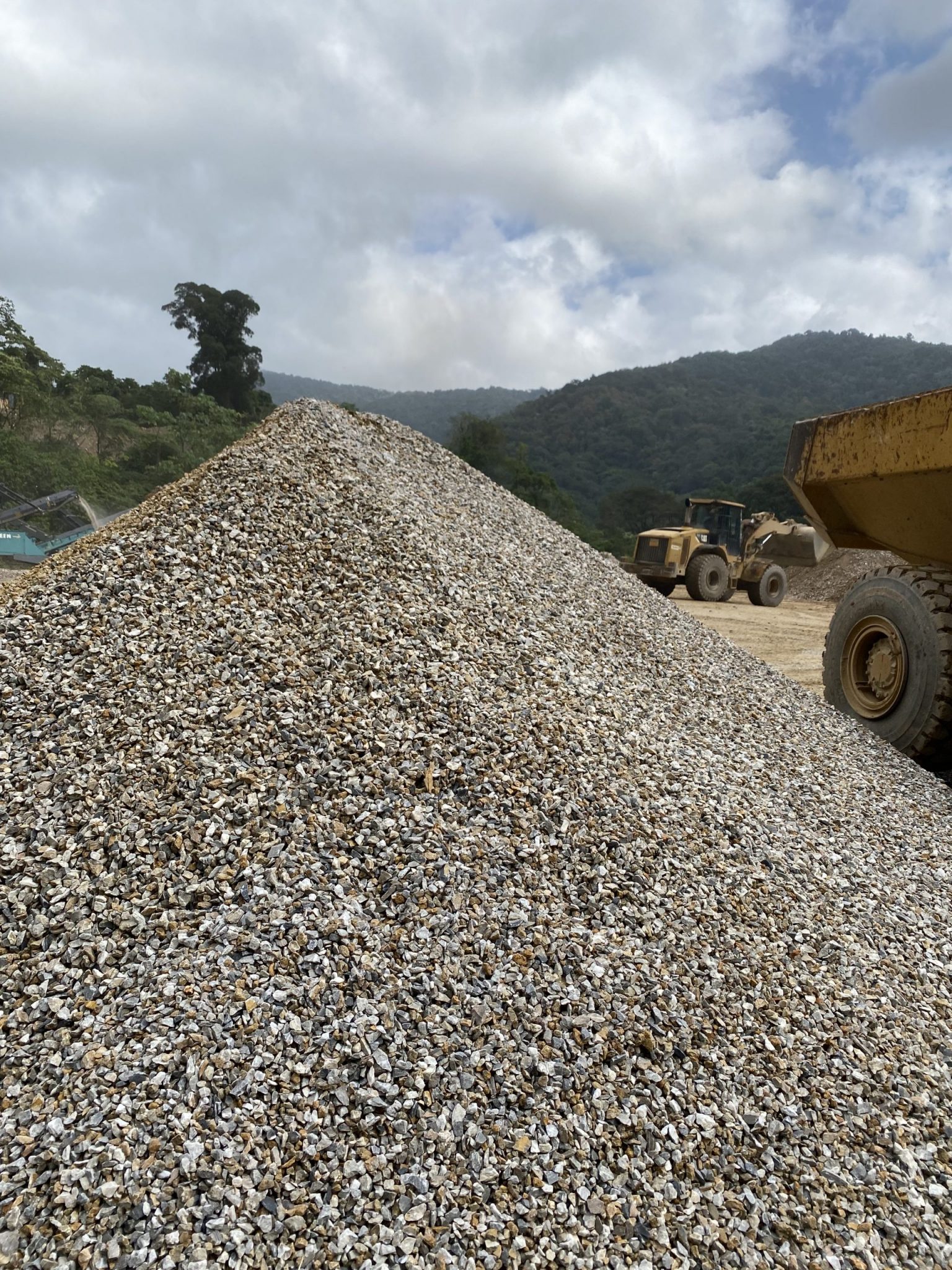This image showcases a sizable stockpile of processed aggregate—ready for transportation and use in various construction applications. Visible in the background are loaders and haul trucks at work, underscoring the company’s production capacity and commitment to meeting national infrastructure needs.
